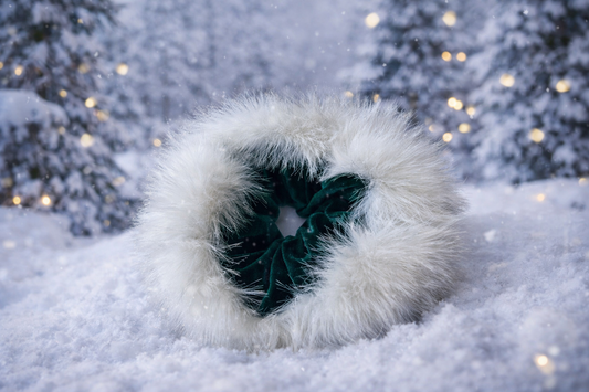 White fluffy scrunchie with a green bow on a snowy background