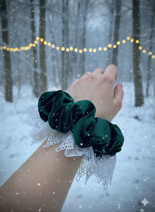 Hand wearing green scrunchies with a snowy forest background. side view